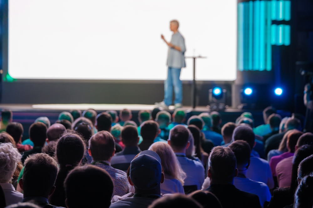 Speaker,Presents,At,A,Conference,While,A,Large,Audience,Listens